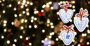 floating-josephine-desine-ceramic-painted-heart-ornaments-with-red-velvet-bow-on-twinkling-lights-background